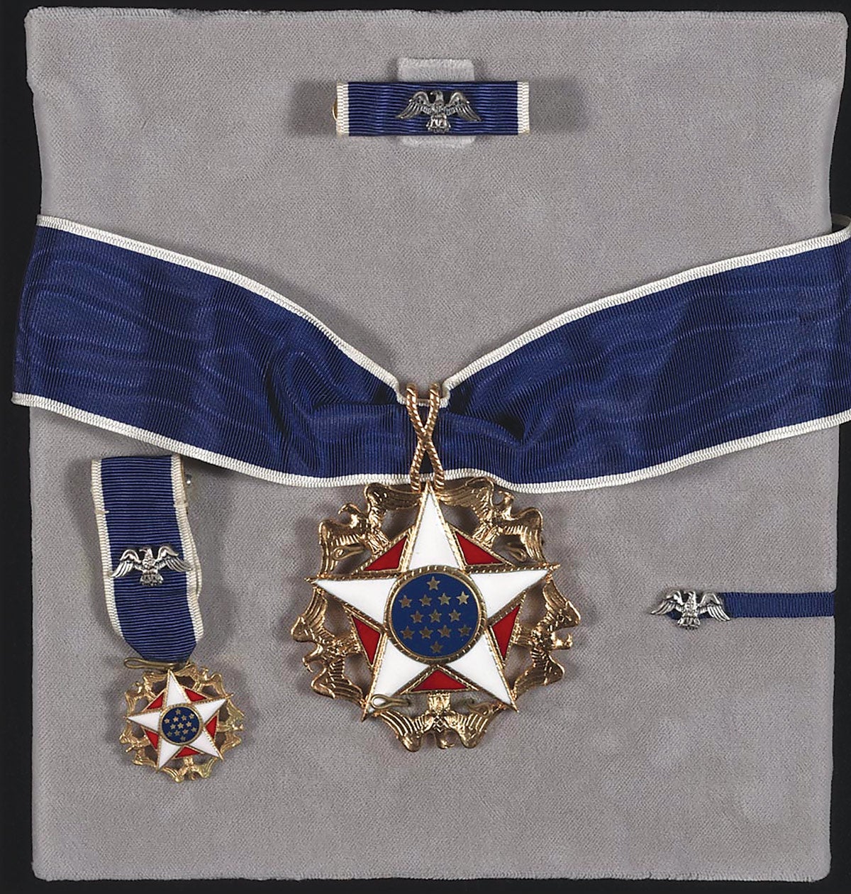 The Presidential Medal of Freedom is a neck order on a dark blue ribbon with White edge stripes. The awarded set also includes a miniature version for formal dress.